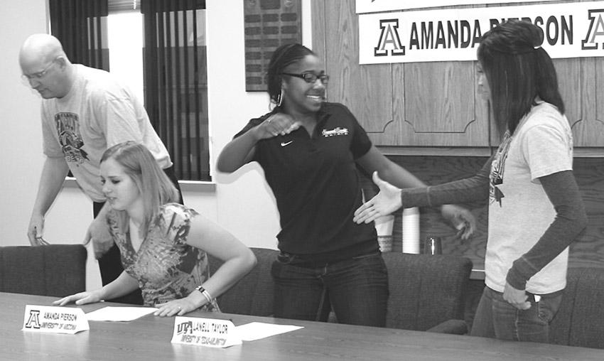 Crusader photo/James McElvania
Lanelle Taylor, center, celebrates her signing with assistant coach Kim Ortega, right. Taylor signed to the University of Texas Arlington. Teammate Amanda Pierson, seated at table, signed to play at the University of Arizona.