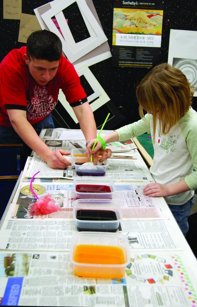 Jose Sanchez helps Ashleigh Parker, a participant of Children’s Art Day, dye her flower made of coffee filters and pipe cleaners. Children’s art day was sponsored by Kylix, and the money raised that day will go towards Kylix’s spring trip to Santa Fe, N.M., April 24-26. Other projects made that day were books, dangling ornaments, coffee filter flowers, relief sculptures, sacks to put projects in and stick people sculptures.