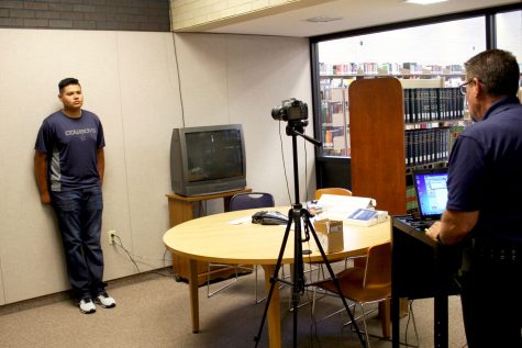 A student listens to all of the ways the new identification cards can be used on campus after posing for ID picture.