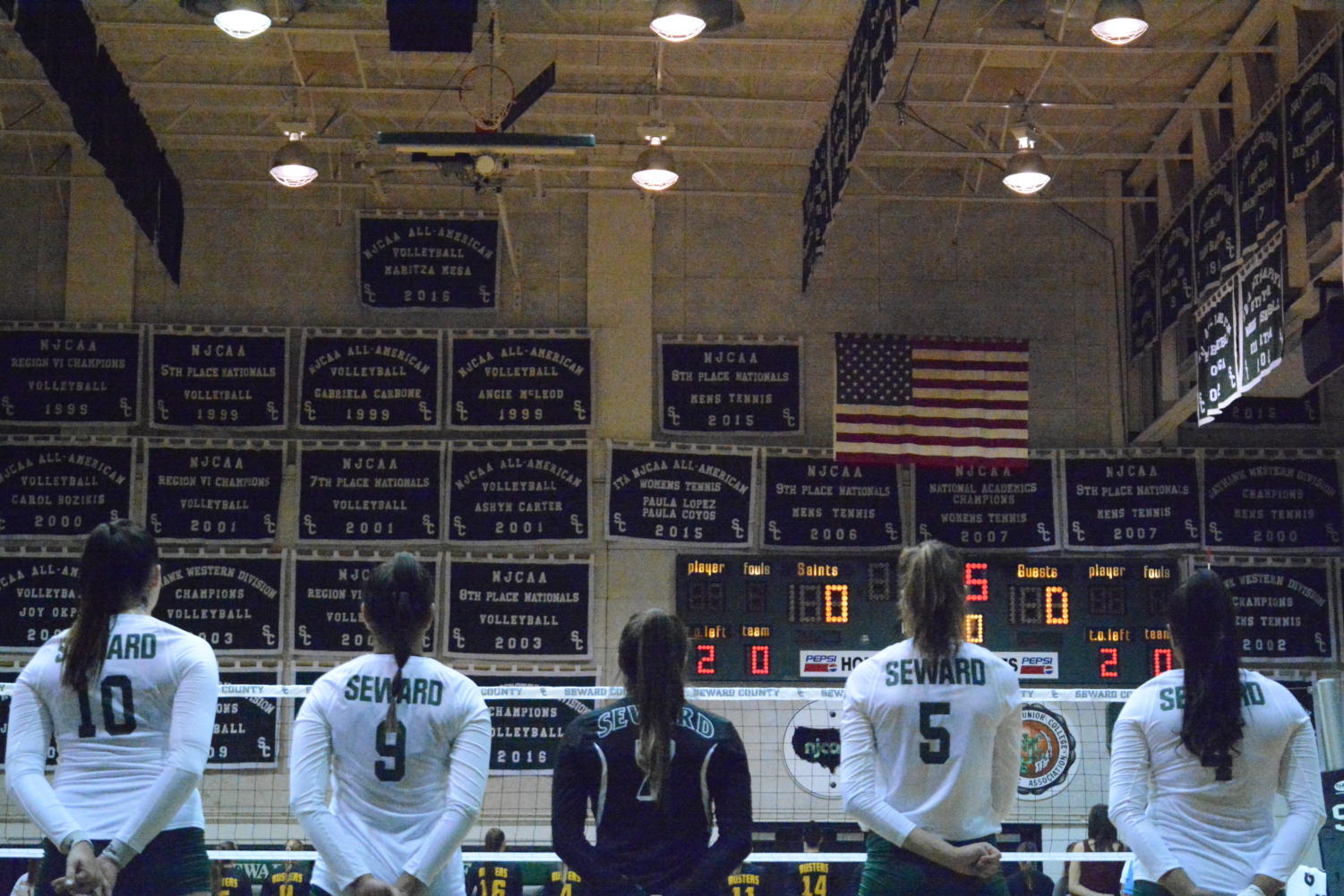 The Lady Saints line up for a pre-season game for the National Anthem. The banners in the Greenhouse are constant reminders of what's expected of their team — to win championships.