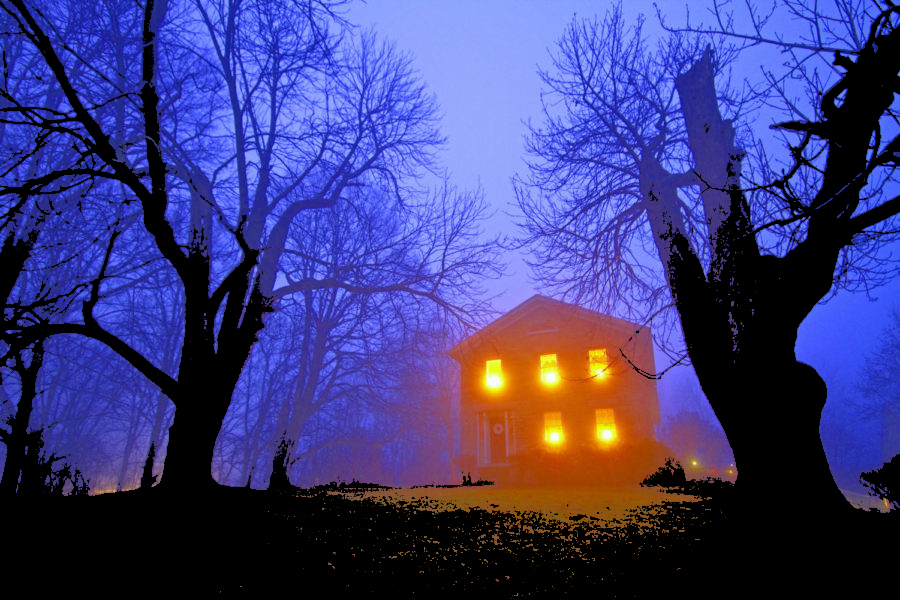 Old stone house with candles in window on foggy gloomy night, Skaneateles, New York.
