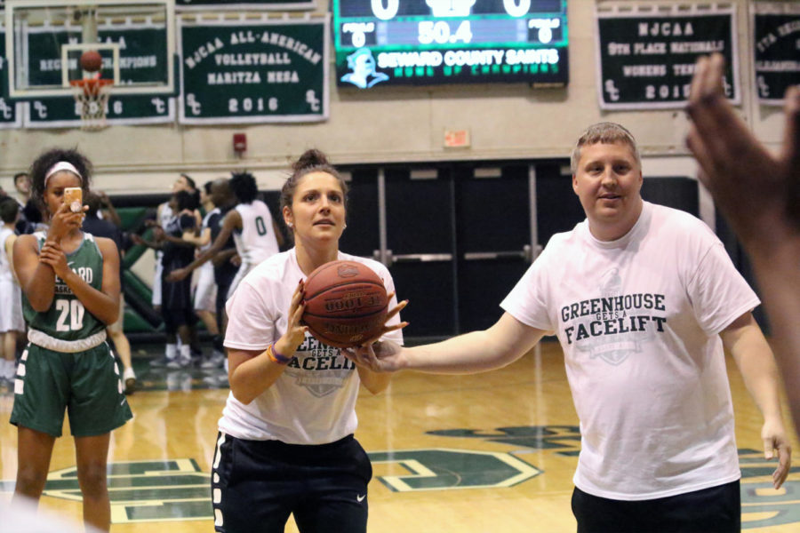 Head coach, Austin Mefford hands the ball to his assistant coach, Lizzie Nessling during the coaches free throw contest. The mens coaches won.