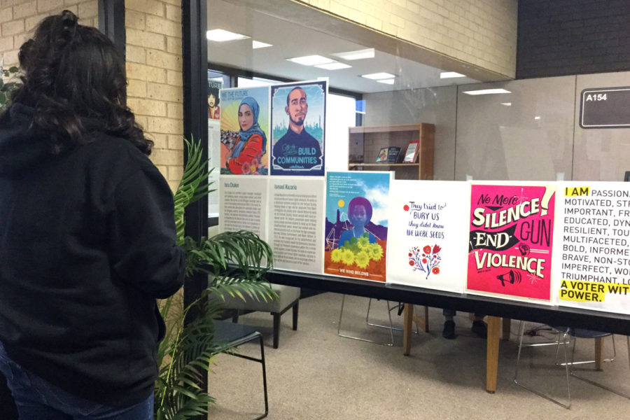 Freshman education major Gissella Garcia takes a quick look at activism posters hung up in the SCCC library. 