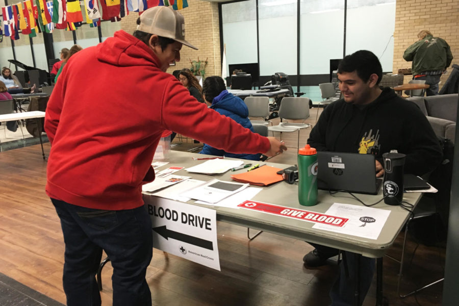 Adan Gonzalez is working as a volunteer at the blood drive. Jonathan Ibarra  is signing in to donate blood and save lives.