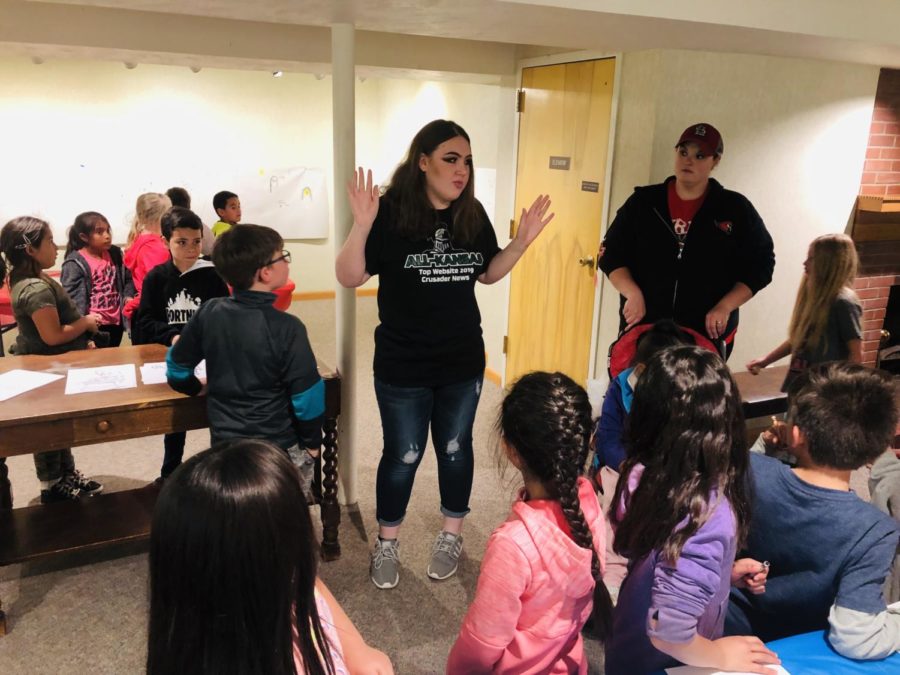 Cheyenne Miller explains the coloring activity to elementary students from Turpin, Oklahoma. The freshman English major volunteered with Crusader at the Baker Arts Center during a Sea Lions exhibit.