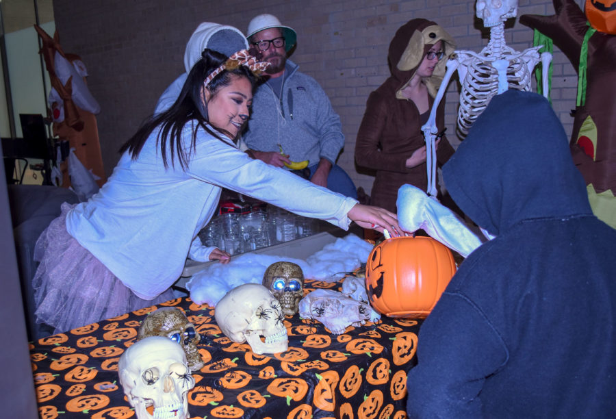 Nayeli Galan, Liberal freshman, hands out candy to children. The cheer team hosted a ping pong ball toss game for the trick-or-treaters..