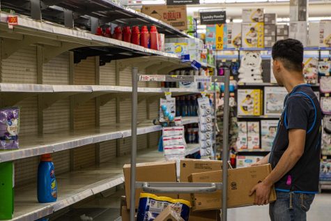 Jonathan Jacquez, Walmart employee and high schooler, tries to stock chemical cleaning products in an aisle half empty due to customers panic buying.