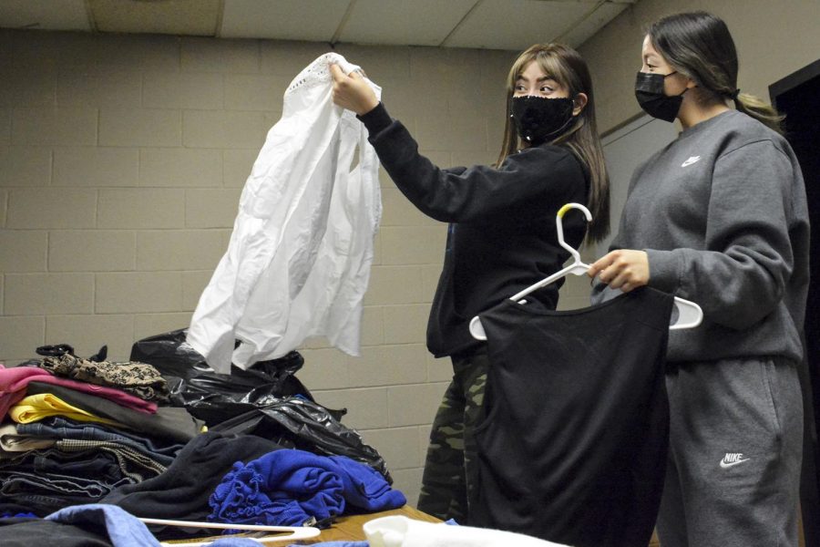 Elisa Bolanos, business management major, and Hannah Rosales, business administration major, sort through donated clothes in the back of the store. The two PBL club members try to create outfits that might go together and appear professional.