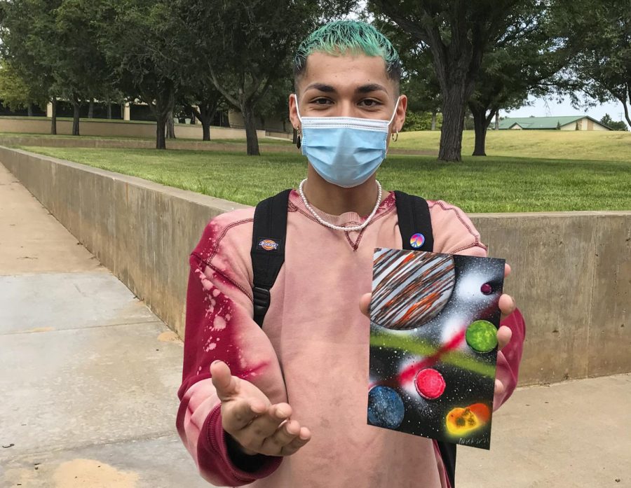 Adrian Mendoza, sophomore accounting major, shows off his spray paint art. It took three minutes for this solar system to be painted.