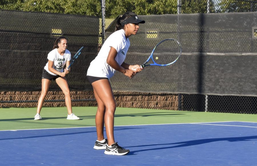 Carol Mora and Justine Lespes play doubles tennis in Oklahoma City. The duo wait for a serve from the opposing team.