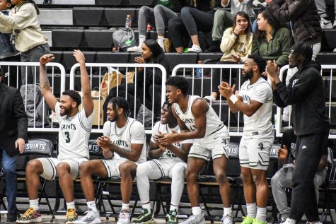 The Saints bench erupts in cheers as a teammate throws down a dunk in the 68-61 win against Dodge City Community College Wednesday in the Green House.