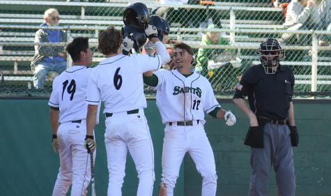 Javier Gomez, Ranse Radtke and Jase Schneider celebrate by colliding their helmets together. Saints baseball lost the first game with a score of 7-2, and then they won their second game with a score of 11-0.
