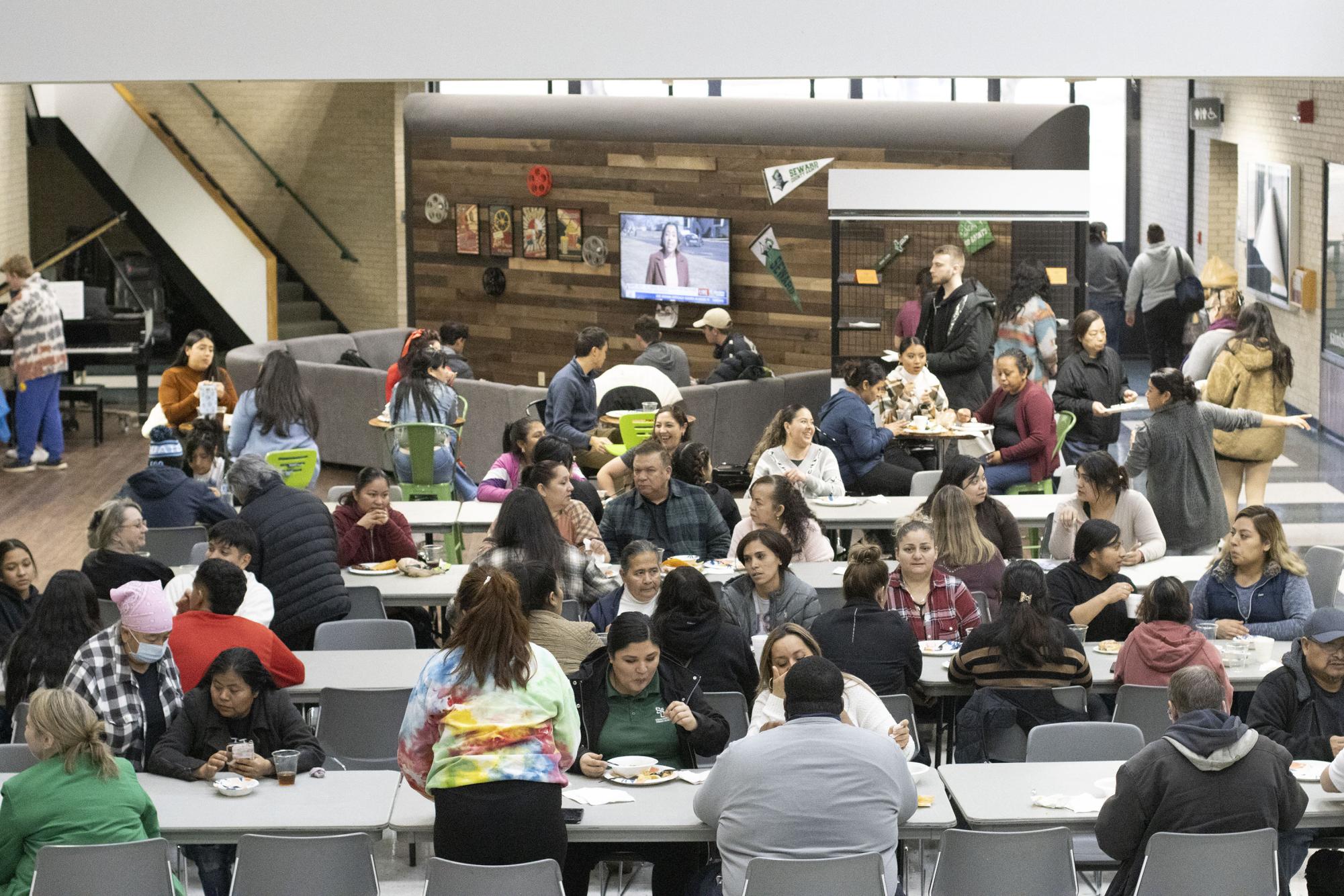 People talking at their tables, eating plates of diverse food at The Student Union. The food available included various rice, pasta, meats, and drinks.