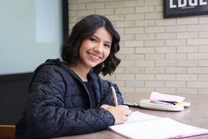 Mejia poses for a picture as she takes notes. Outside of her classes, she is the secretary of HALO, where she prepares presentations and meeting agendas.