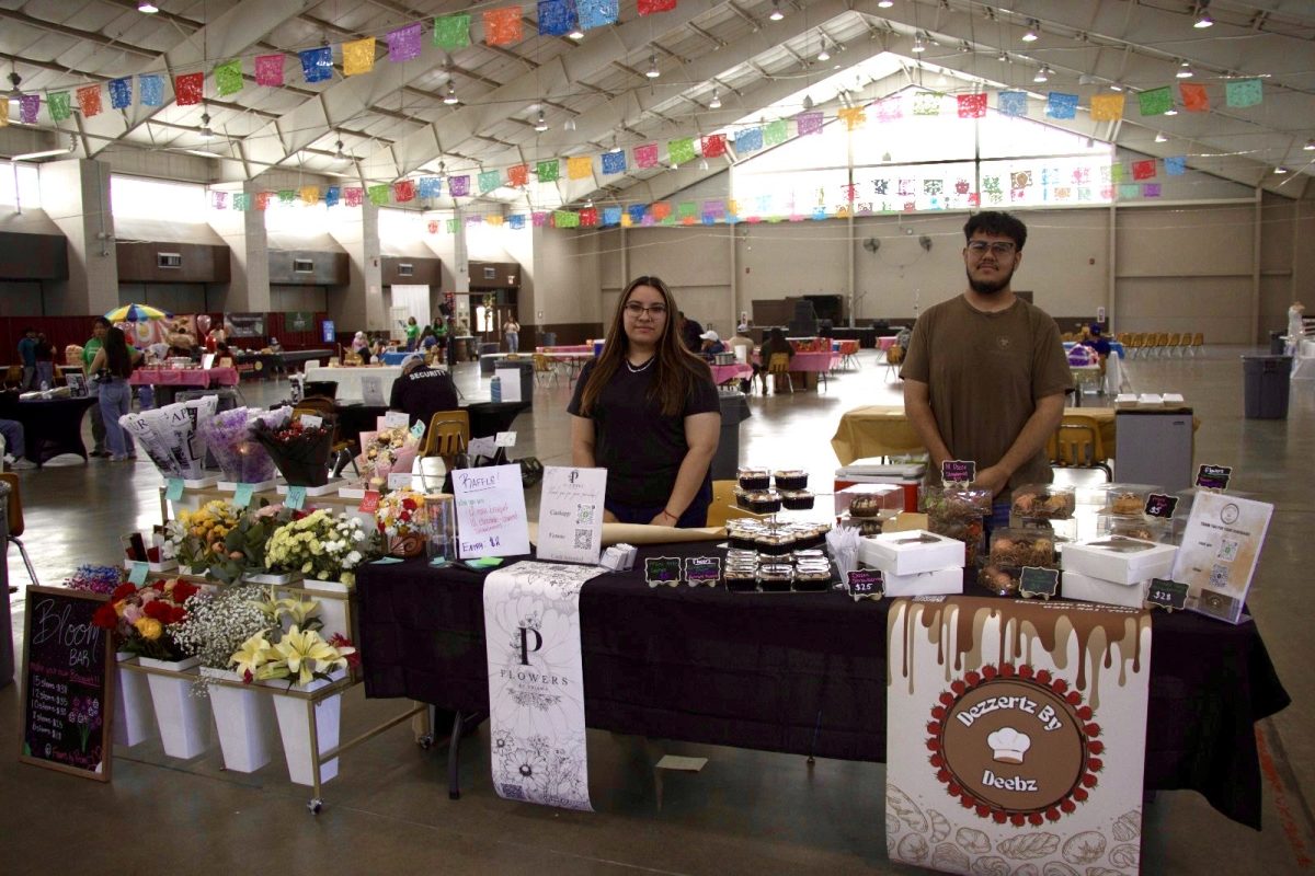 Vendors from “P Flowers” and “Dezertz by Deebz” stand behind their booth showcasing fresh floral arrangements and homemade desserts during the Celebrate and Connect Fest held in the Activity Center, Liberal, Kansas, under papel picado banners.