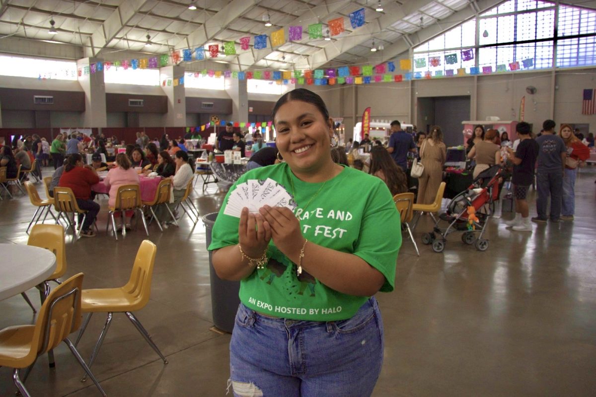 Melissa Maldonado at Celebrate and Connect Fest holds up HALO business cards during the expo, which brought together families, local businesses, and entrepreneurs in a festive and cultural atmosphere.
