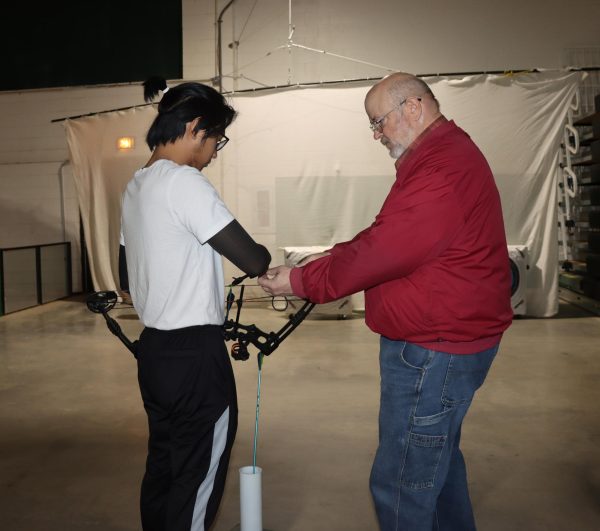 Instructor Craig Dusek teaches the student how to properly hold a bow and aim at the target. 