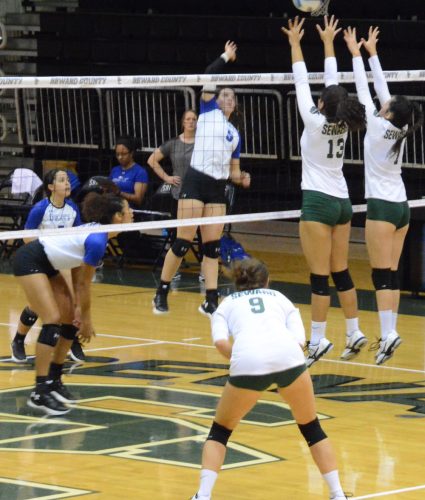 Freshman Dorianne Lebron and Laura De Pra attempt to block a Lady Beaver's hit. The Lady Saints finished with a season low of only two blocks.