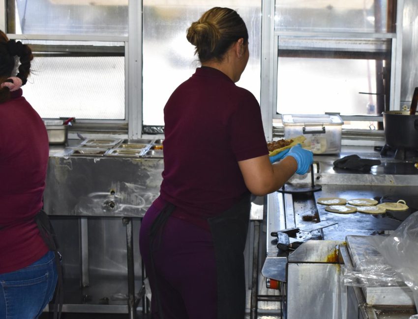The cooks at Las Delicias prepare tacos to take to customers.